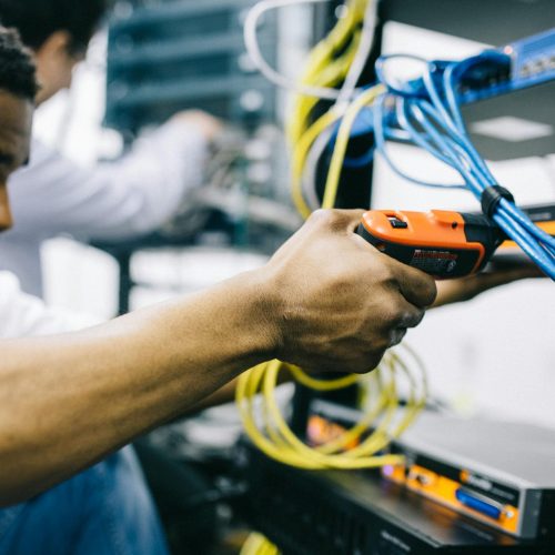 An engineer inspects network cables and connections in a server room, focusing with precision.